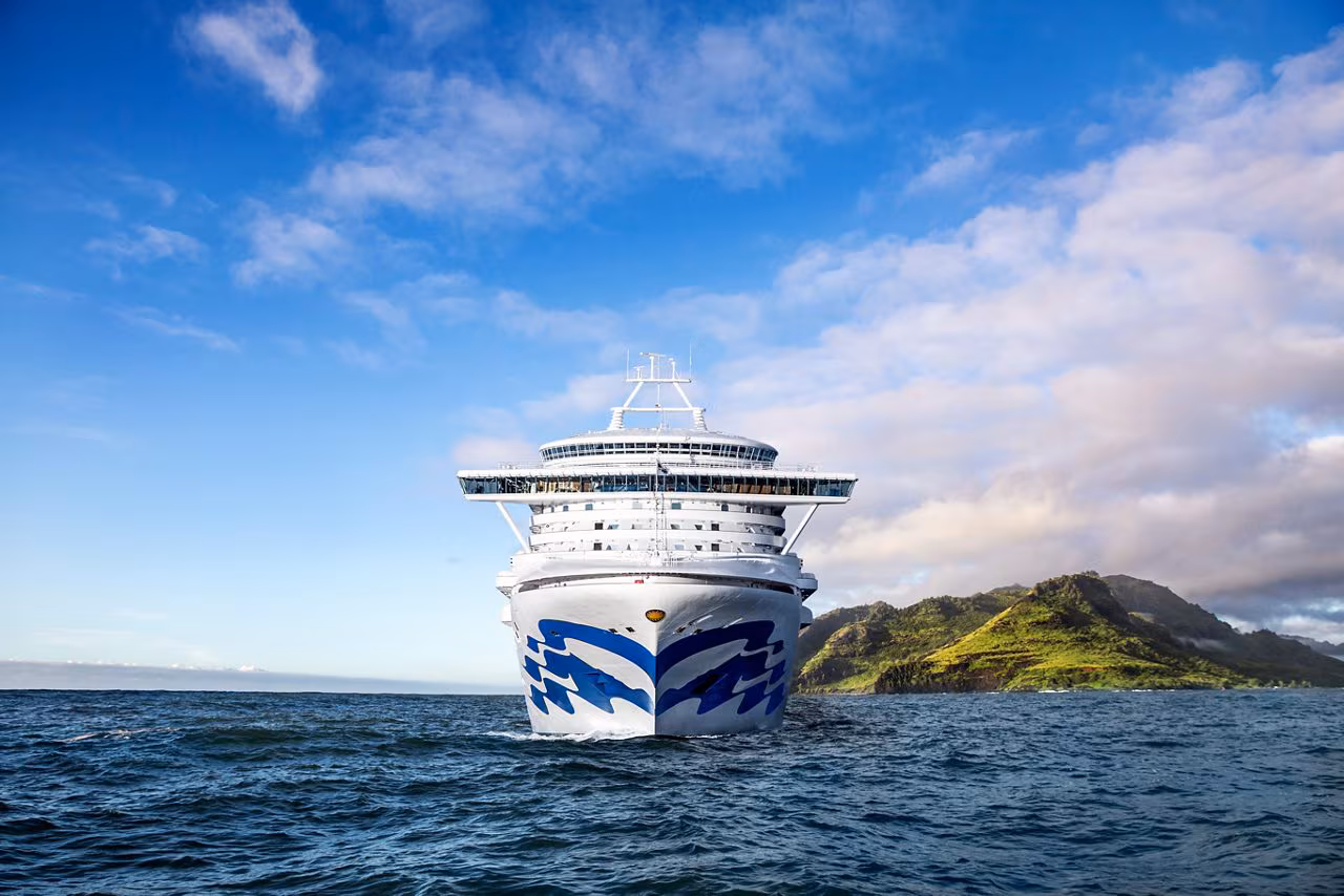 A Princess ship sailing beside a sunlit island